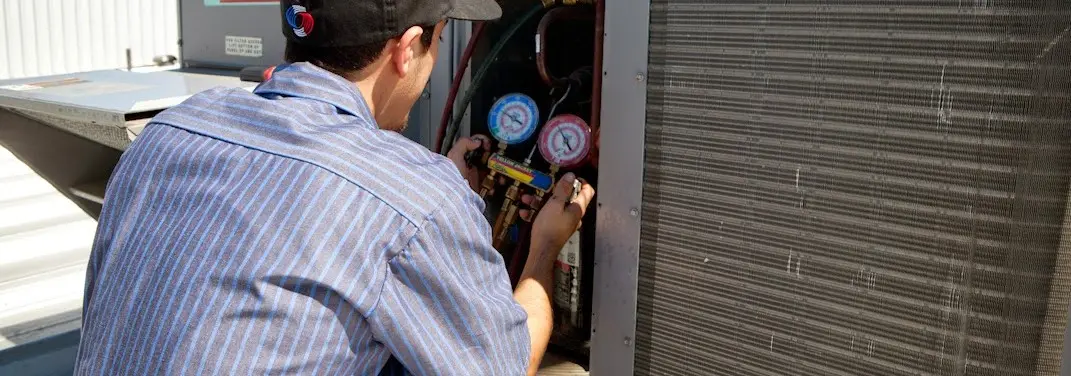 HVAC technician servicing a condenser unit in North St. Paul